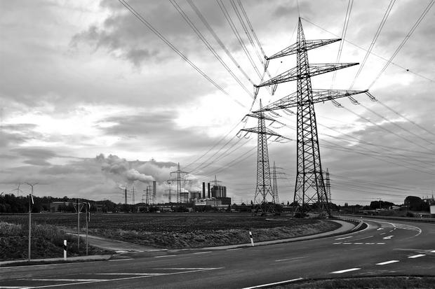 Power-pole-with-power-station-in-background-black-and-white