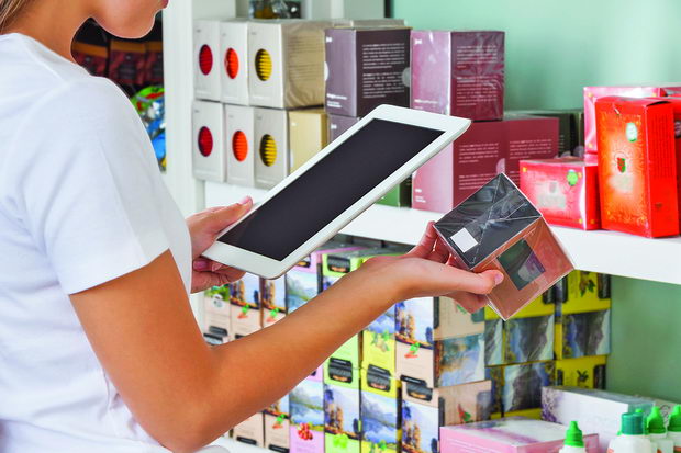 Midsection of young woman scanning barcode through digital table